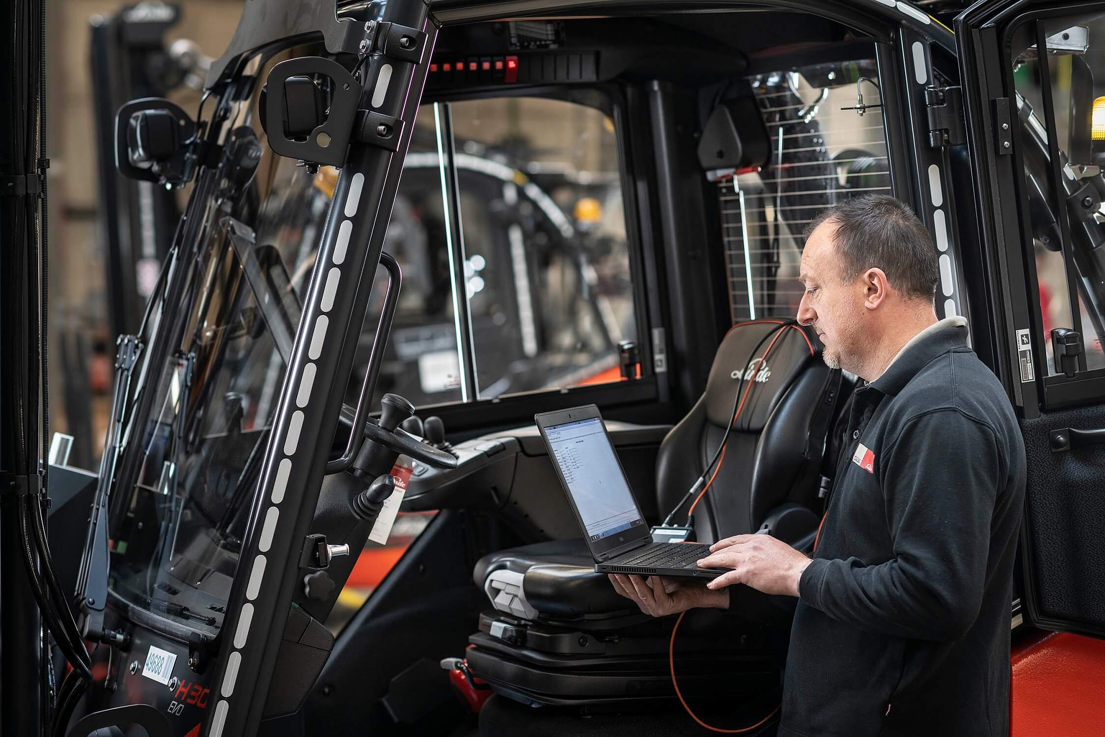 Technieker met laptop aan heftruck